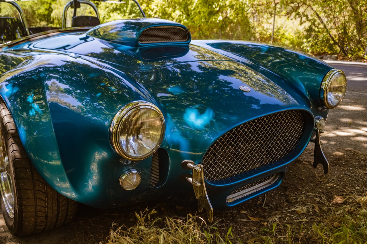 A vintage Shelby Cobra sports car parked outdoors in a scenic setting.