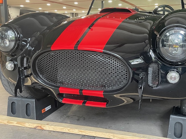 Opposite angled view of the installed grille on a black Cobra replica with red racing stripes