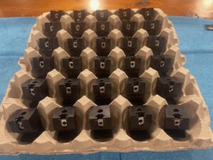 Updated black aluminum Cobra-Grille mounting blocks arranged in a tray