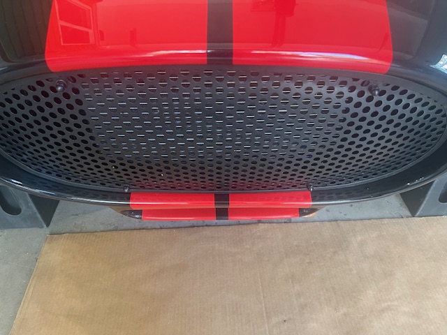 Angled view of the 3/8-inch round-perforation grille installed in a black Cobra with red stripes